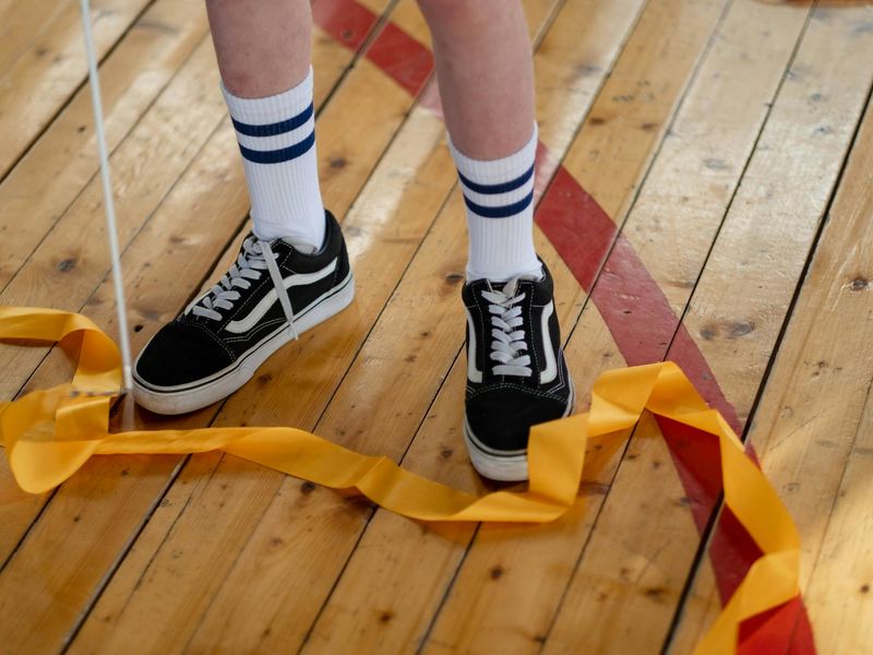 Athletic shoes on a wooden floor in a sunlit gym